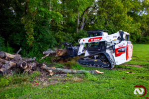 Bobcat machine removing logs during land clearing